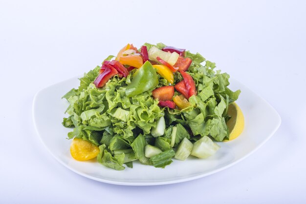 Deliciosa salada de vegetais com folhas em um prato branco com fatias de pimentão por cima