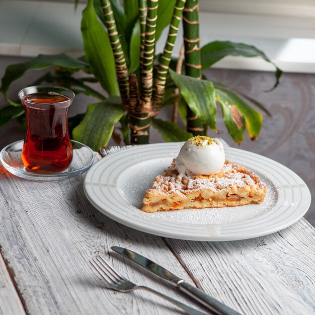 Deliciosa sobremesa em um prato com chá, vista de alto ângulo de plantas em um fundo branco de madeira