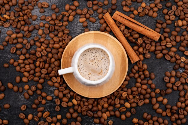 Deliciosa xícara de café cappuccino, rodeada por grãos de café torrados na pedra preta
