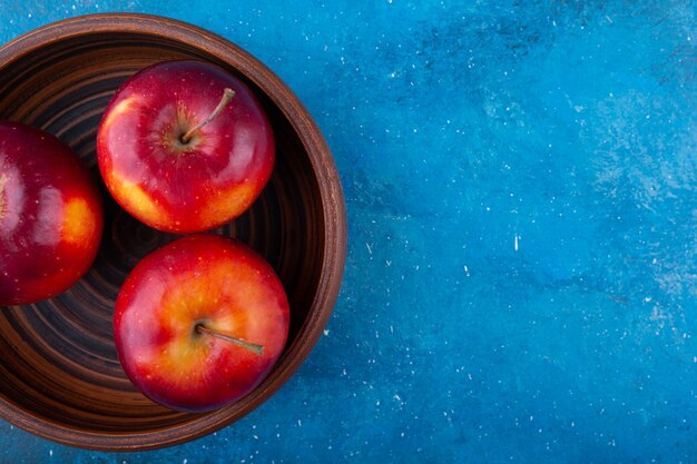 Deliciosas maçãs vermelhas brilhantes colocadas em uma tigela de madeira.