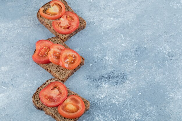 Deliciosas torradas com fatias de tomate em um fundo cinza.