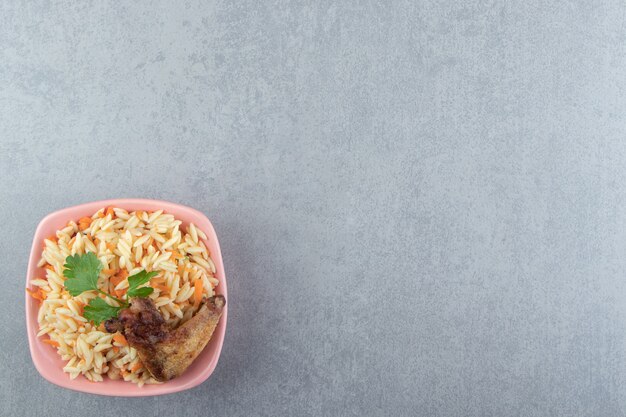 Delicioso arroz com asa grelhada em uma tigela rosa.