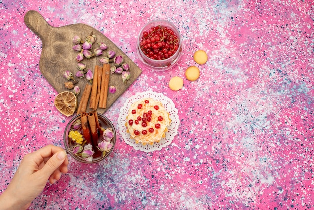 Delicioso bolo com creme com cranberries frescas, canela e chá na mesa roxa