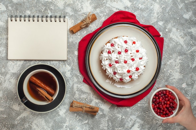 Delicioso bolo cremoso decorado com frutas em uma toalha vermelha e uma xícara de chá preto