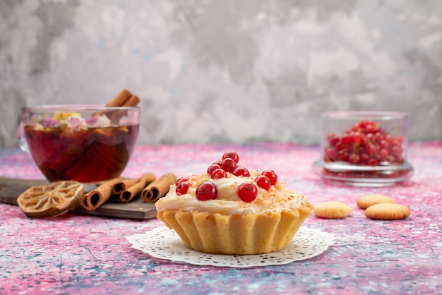 Delicioso bolo de creme com cranberries frescas, juntamente com canela e chá na mesa de trabalho leve e doce