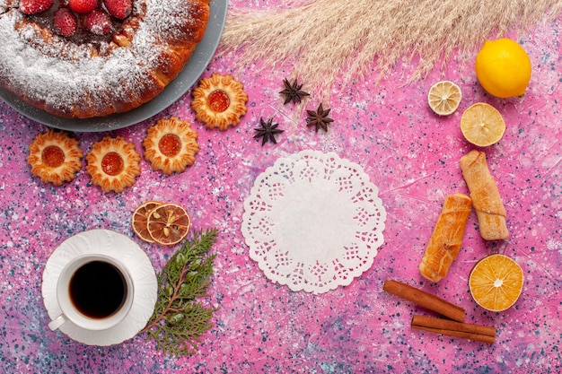 Delicioso bolo de morango com biscoitos de rosca e uma xícara de chá no fundo rosa