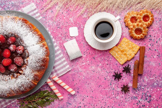 Delicioso bolo de morango com uma xícara de chá de canela na superfície rosa