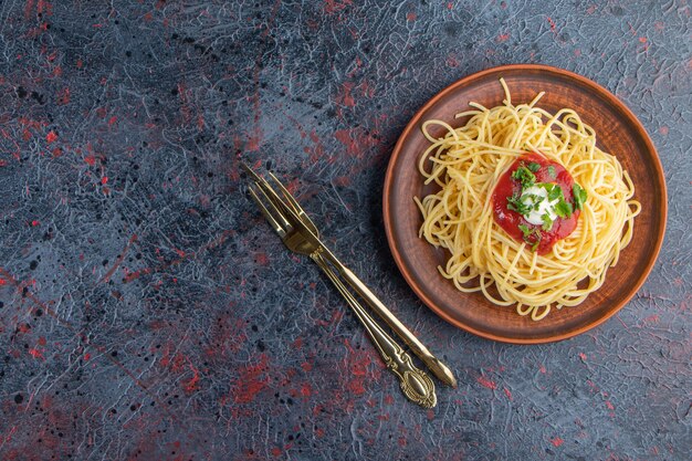 Delicioso espaguete com molho de tomate na placa de madeira com talheres.