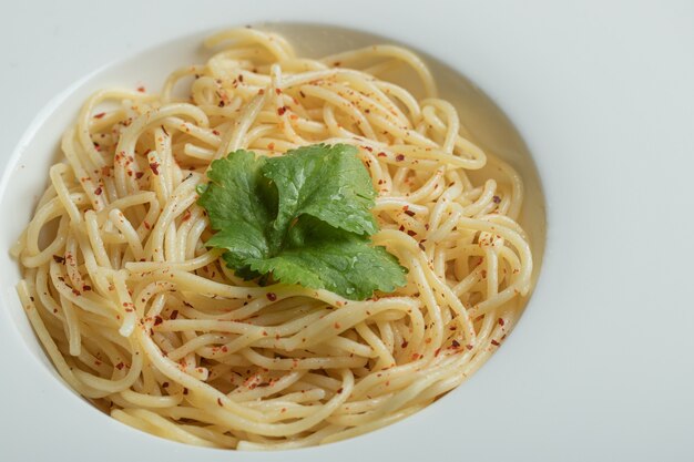 Delicioso espaguete com verduras em um prato branco.