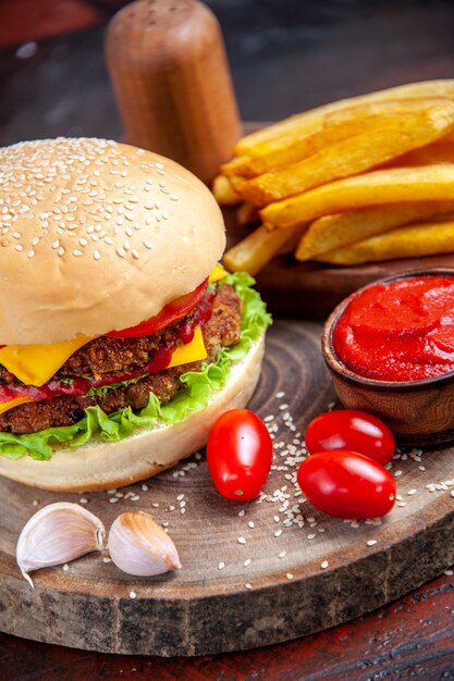 Delicioso hambúrguer de carne com batata frita em fundo escuro de vista frontal