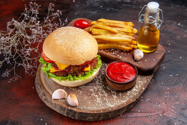 Delicioso hambúrguer de carne com batata frita em fundo escuro de vista frontal