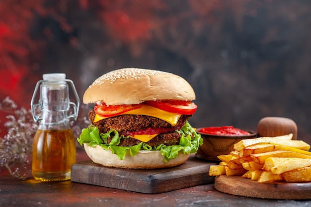 Delicioso hambúrguer de carne com batata frita em piso escuro de frente