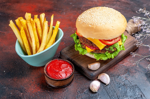 Delicioso hambúrguer de carne com batata frita em piso escuro de frente