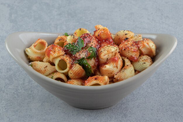 Delicioso macarrão conchiglie com molho de tomate em uma tigela de cerâmica.