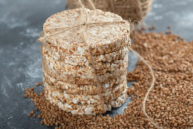 Delicioso pão crocante e trigo sarraceno cru na superfície de mármore