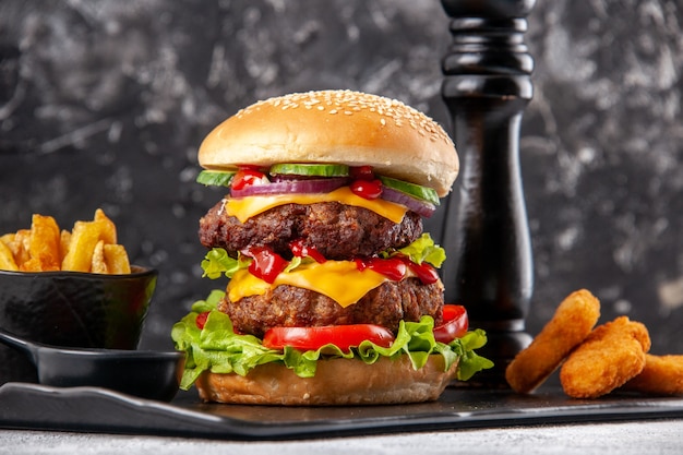 Delicioso sanduíche caseiro e batatas fritas com ketchup nuggets de frango no quadro negro sobre superfície cinza