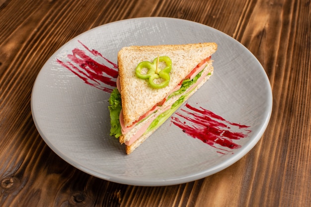 delicioso sanduíche com salada verde de tomate e presunto dentro do prato no marrom