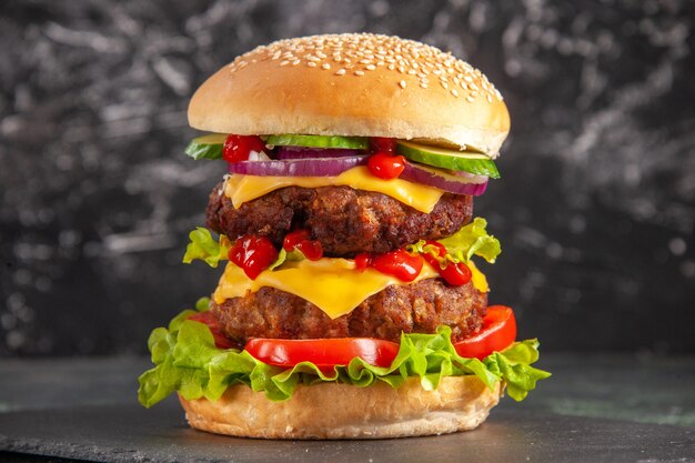 Delicioso sanduíche de carne com tomate verde na superfície escura.