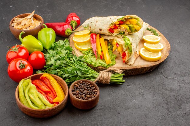 Delicioso sanduíche de carne shaurma fatiado com limão e verduras no espaço escuro de frente