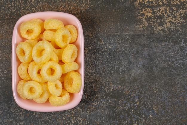 Deliciosos anéis de cereais em uma tigela rosa.