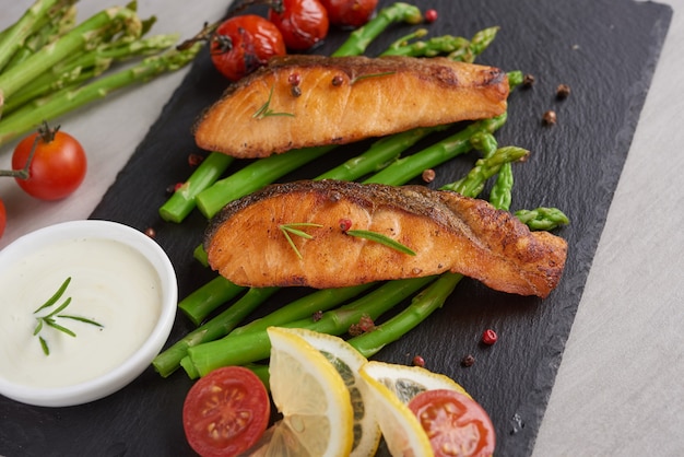 Foto grátis deliciosos aspargos verdes sazonais e salmão fumado fatiado em prato rústico