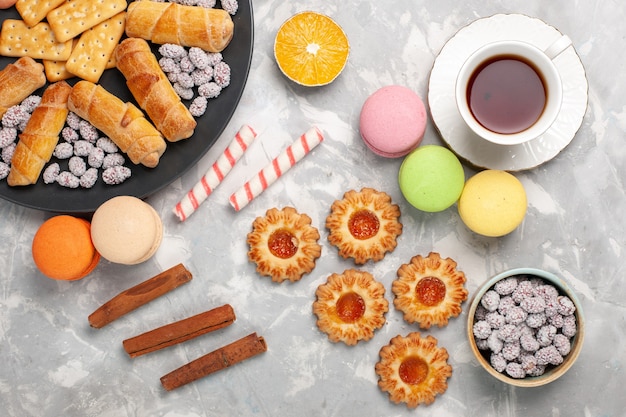 Deliciosos bagels com bolachas, macarons e uma xícara de chá na mesa de mesa de biscoito branco claro, deliciosos bagels com biscoitos doces crocantes