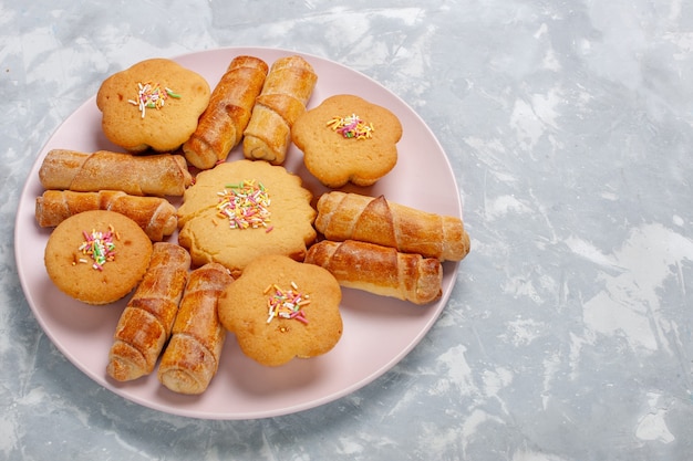 Foto grátis deliciosos bagels com bolos em frente ao prato em uma mesa branca
