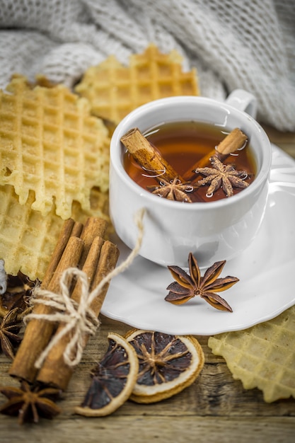 deliciosos biscoitos e uma xícara de chá quente com um pau de canela e uma colher de açúcar mascavo na madeira