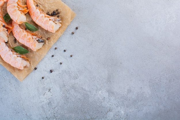 Foto grátis deliciosos camarões com fatias de limão e pimenta em papel vegetal