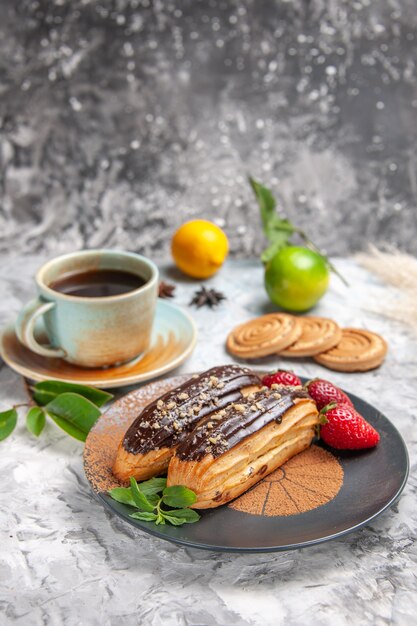 Deliciosos choco eclairs de frente para o chá no bolo de sobremesa de biscoito de mesa branca