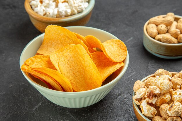 Deliciosos cips de queijo com diferentes petiscos em fundo escuro de vista frontal