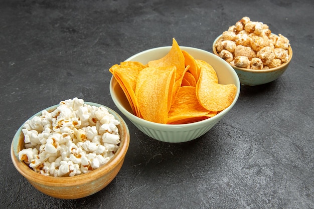 Deliciosos cips de queijo com diferentes petiscos em fundo escuro de vista frontal