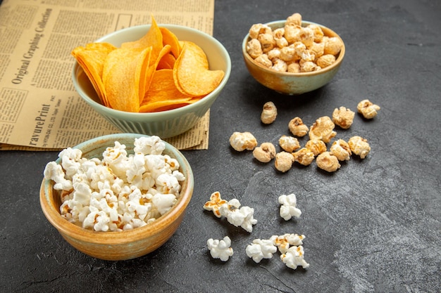 Deliciosos cips de queijo com diferentes petiscos em fundo escuro de vista frontal