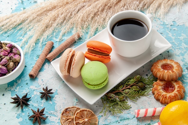 Deliciosos macarons franceses com uma xícara de chá e biscoitos na superfície azul de frente