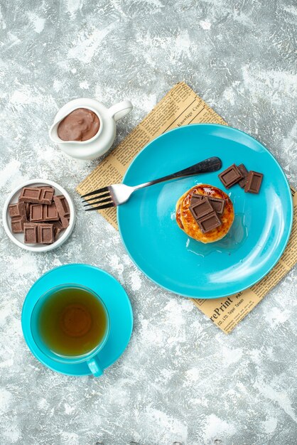 Deliciosos muffins de vista de cima com uma xícara de chá e chocolate sobre fundo claro