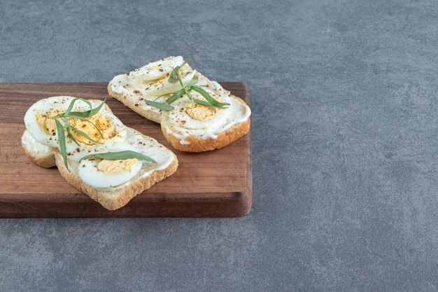 Deliciosos ovos cozidos com torradas de pão na placa de madeira.