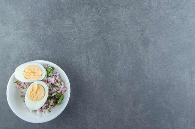 Deliciosos ovos cozidos e salada fresca em uma tigela branca.