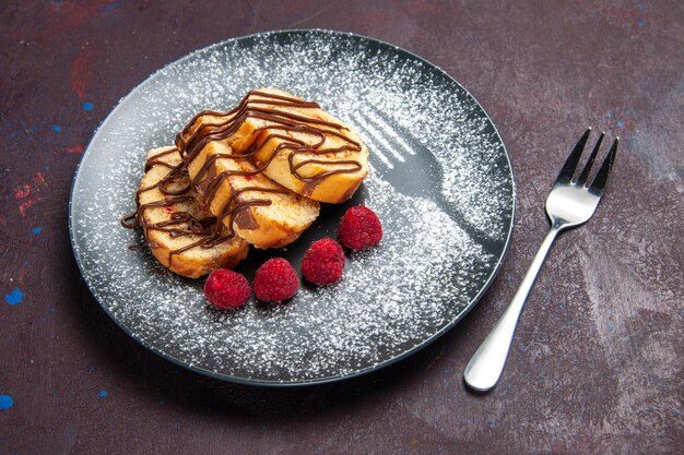 Deliciosos pãezinhos doces fatiados em fatias para o chá dentro do prato no espaço escuro