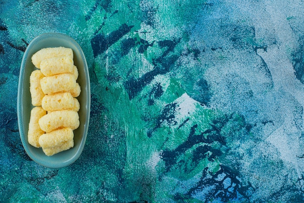 Deliciosos palitos de milho doce em um prato, na mesa azul.