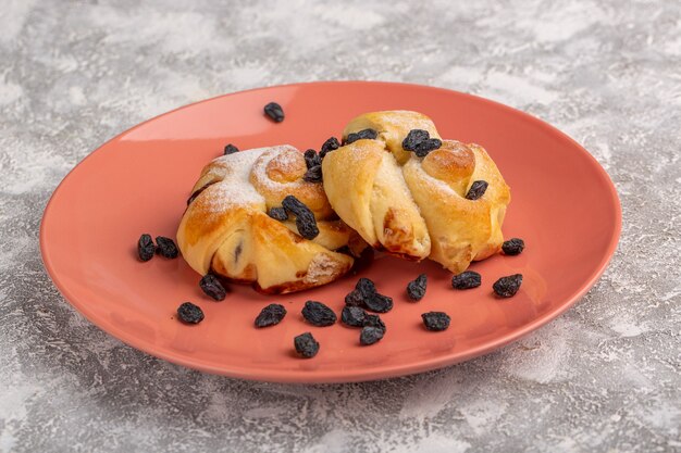 Deliciosos pastéis de frente com recheio dentro do prato junto com frutas secas na mesa branca, bolo de açúcar doce assado