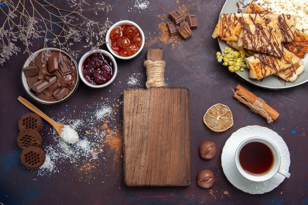 Deliciosos pastéis doces com uma xícara de chá na mesa escura Bolo de biscoito Bolo De Açúcar Doce Chá