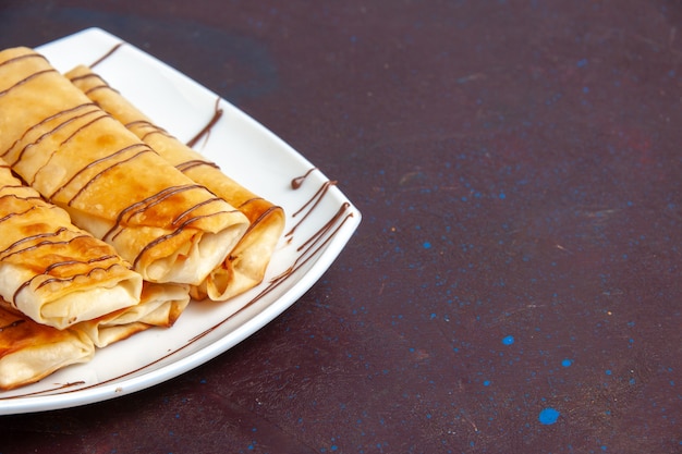 Deliciosos pastéis doces de frente para dentro do prato no espaço escuro