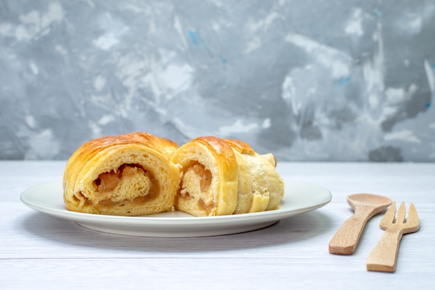 Deliciosos pastéis fatiados dentro do prato com recheio junto com colher de garfo de madeira em branco