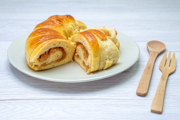 deliciosos pastéis fatiados dentro do prato com recheio junto com colher de garfo de madeira na mesa branca, biscoito biscoito doce açúcar