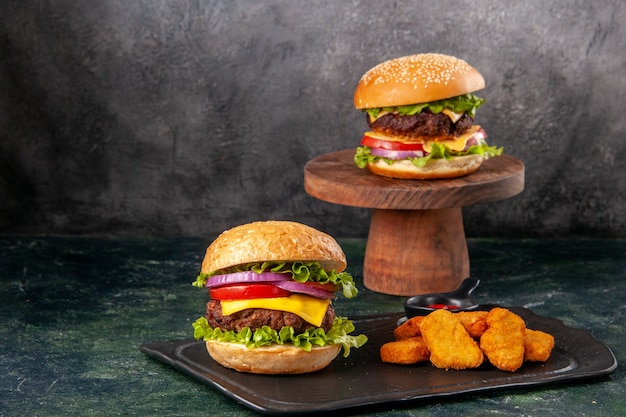 Deliciosos sanduíches de batata frita nuggets de frango na tábua de corte preta frita pimenta na mistura escura colorida superfície desfocada