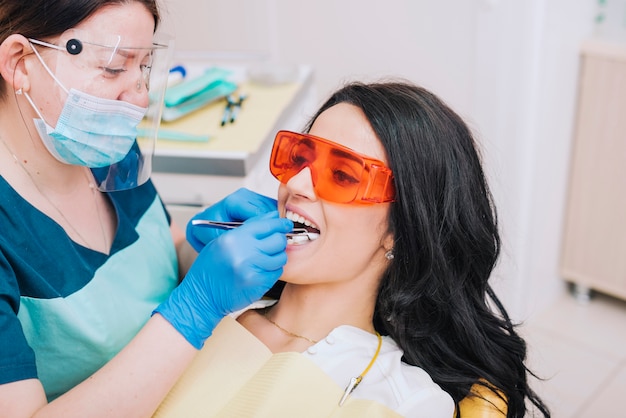 Dentista, colocando a bola de algodão na boca do paciente