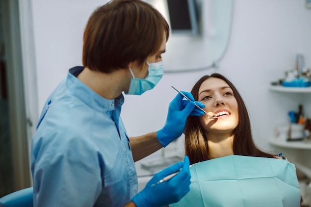 Dentista com espelho verificando dentes da mulher