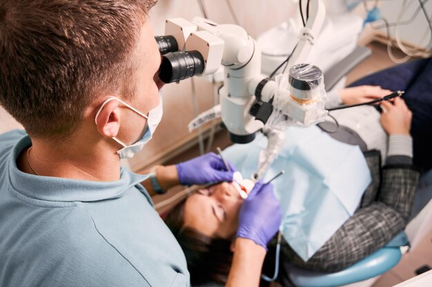 Dentista examinando os dentes da mulher com microscópio diagnóstico