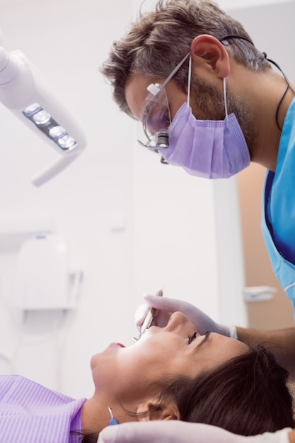 Dentista examinando uma paciente do sexo feminino com ferramentas