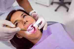 Foto grátis dentista examinar pacientes do sexo feminino dentes com um espelho de boca